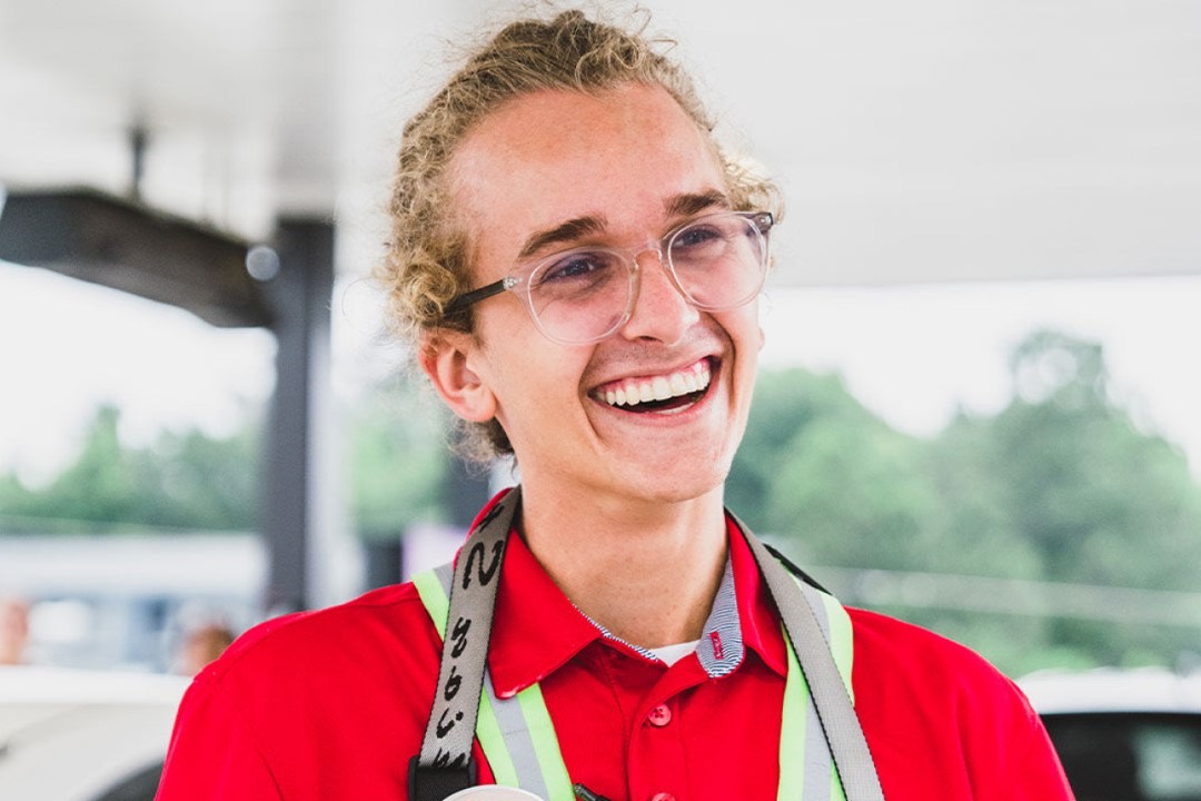 A Chick-fil-A Team Member in a drive-thru safety vest, smiling.
